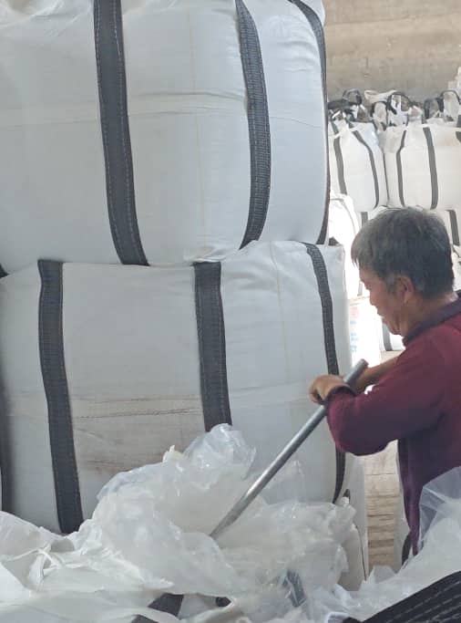 Operator collecting a ceramic proppant sample from a selected bag